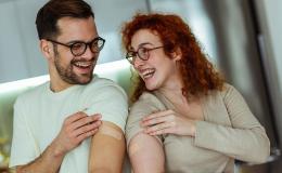 Mężczyzna i kobieta pokazują, że są zaszczepieni, uśmiechy