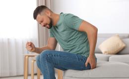 mężczyzna podnosi się chwytając się za pośladek