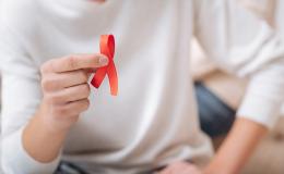 ręka trzymająca czerwoną wstążkę symbol AIDS