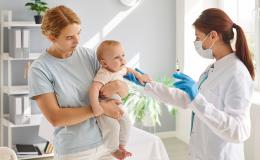 kobieta z małym dzieckiem, lekarka trzyma strzykawkę