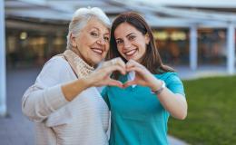 Dwie kobiety w różnym wieku pokazują znak serca