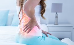 Kobieta trzyma rękę na bolącym kręgosłupie
