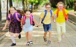 Czwórka dzieci ok. 10 lat z tornistrami, biegnie razem 