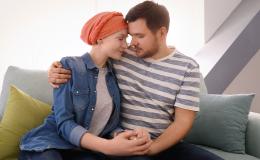 Młody mężczyzna i kobieta z chustką na głowie siedzą przytuleni na kanapie