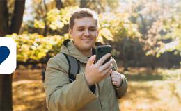 Pan przy kości na spacerze z telefonem, w tle jesienny park