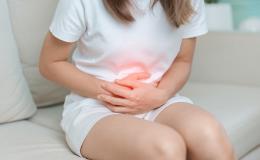 Dziewczyna siedzi i trzyma się za brzuch