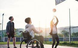 młodzi mężczyźni grają w koszykówkę, jeden jest na wózku