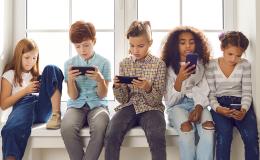 Grupa dzieci ze smartfonami na parapecie