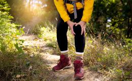 mężczyzna ubrany na sportowo chwyta się za kolano