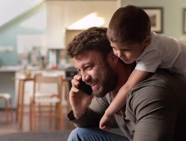 Syn wchodzi na plecy ojcu, który rozmawia przez telefon