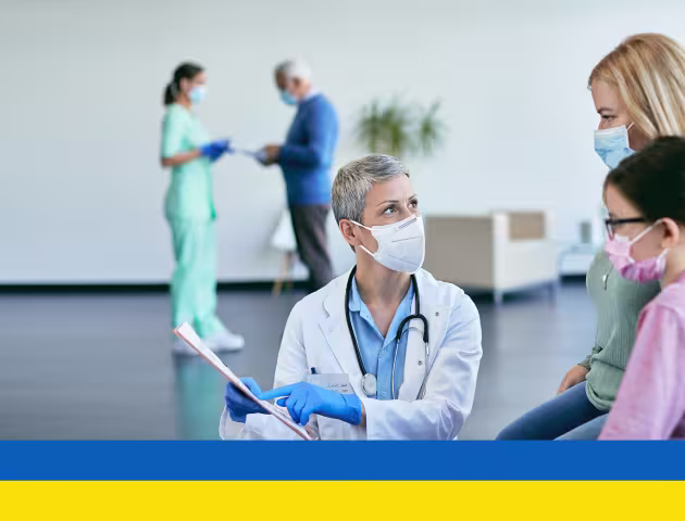 Lekarz pokazuje kartę matce z dzieckiem, flaga ukraińska na dole