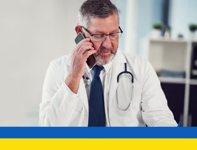 Lekarz rozmawiający przez telefon, na dole ukraińska flaga