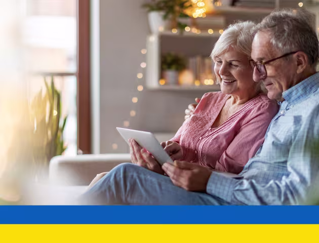 Starsza para na kanapie patrzy na tablet ukr