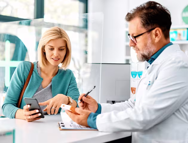 pacjentka z telefonem w aptece rozmawia z farmaceutą