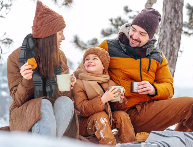 rodzinka w zimowym lesie pije herbatę z termosu