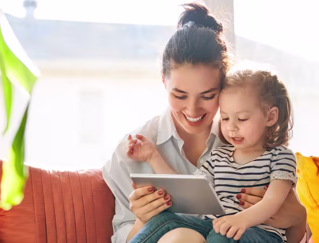 Mama z 2letnim dzieckiem na kanapie, trzyma tablet