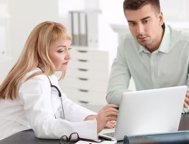 pacjent i lekarka patrzą w laptop