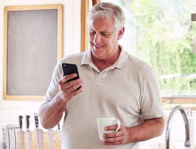 50latek w kuchni patrzy na telefon