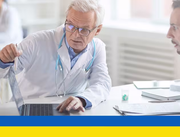 Lekarz pokazuje coś pacjentowi w komputerze ukr
