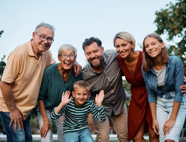 Uśmiechnięta rodzina pozuje do zdjęcia - dziadek i babcia, tata i mama, syn i córka.