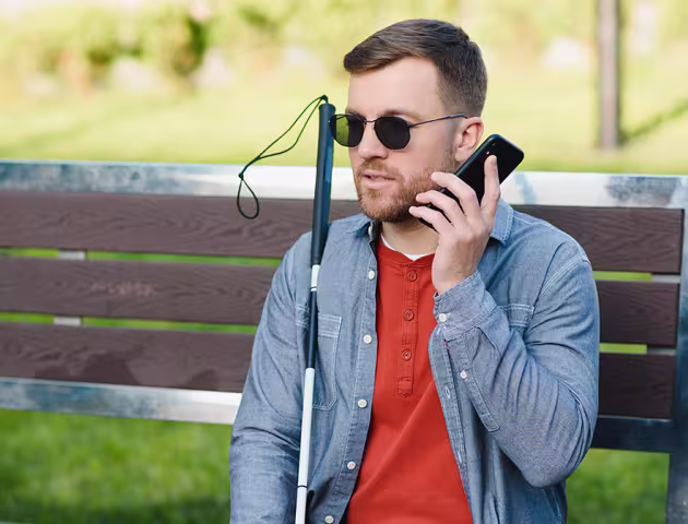 niewidomy mężczyzna z telefonem na ławce