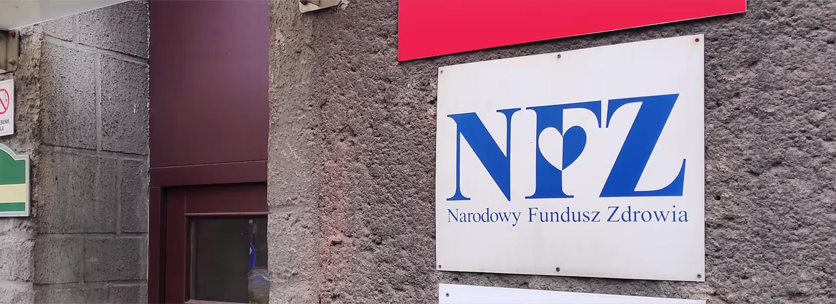 Tabliczka z logo NFZ na ścianie budynku.