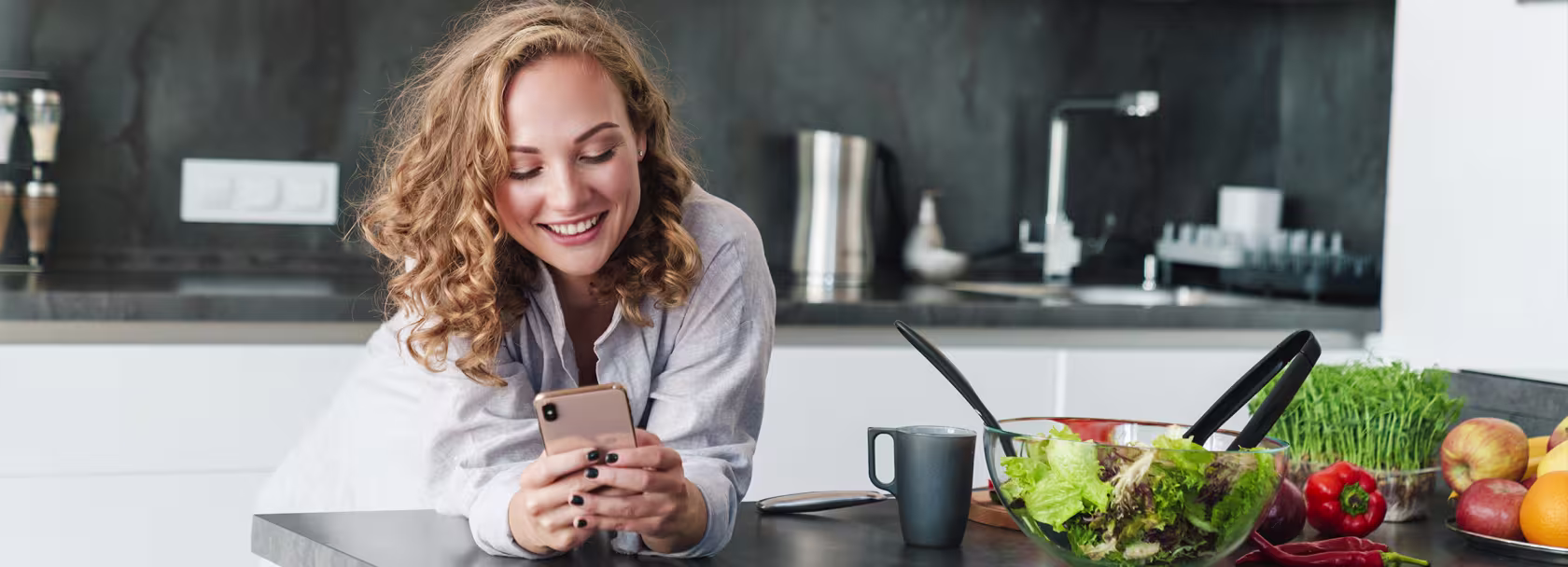 Kobieta w kuchni patrzy na telefon