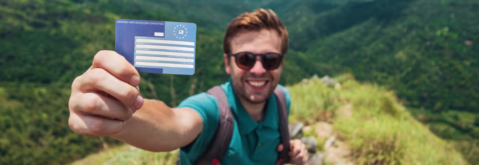 Turysta pokazujący kartę EKUZ. W tle góry