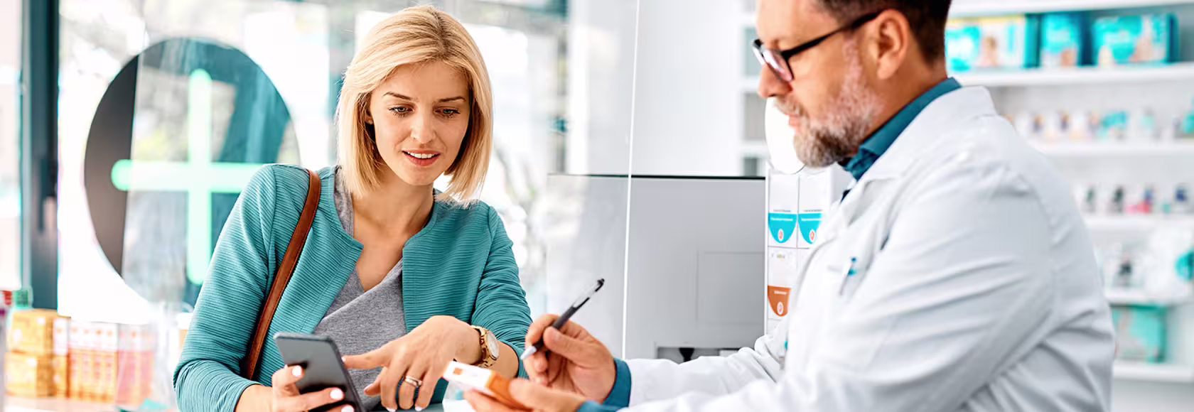 pacjentka z telefonem w aptece rozmawia z farmaceutą
