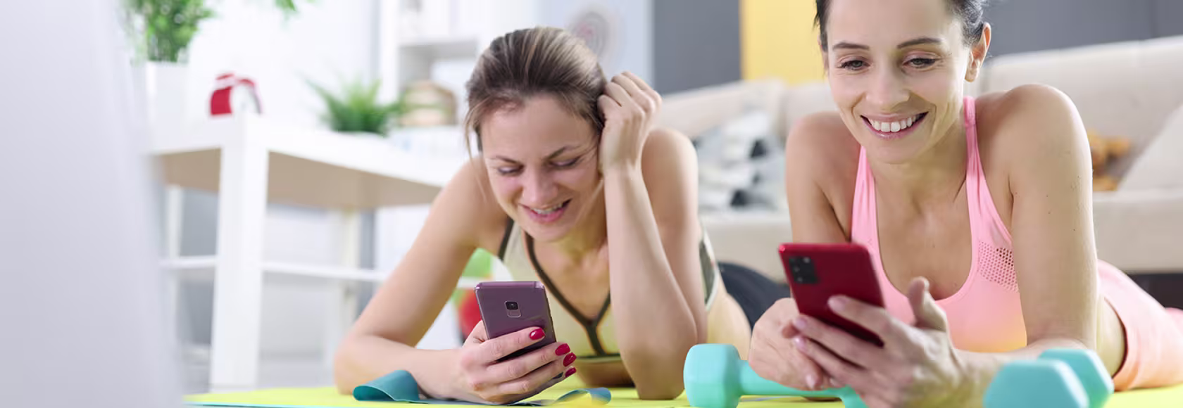 dwie młode dziewczyny ćwiczą w domu z telefonem