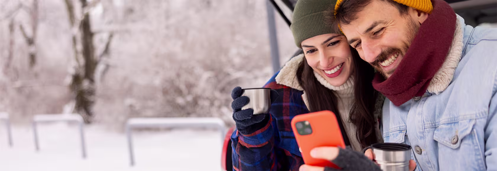 Usmiechnieta para patrzy na telefon, w tle zimowy krajobraz